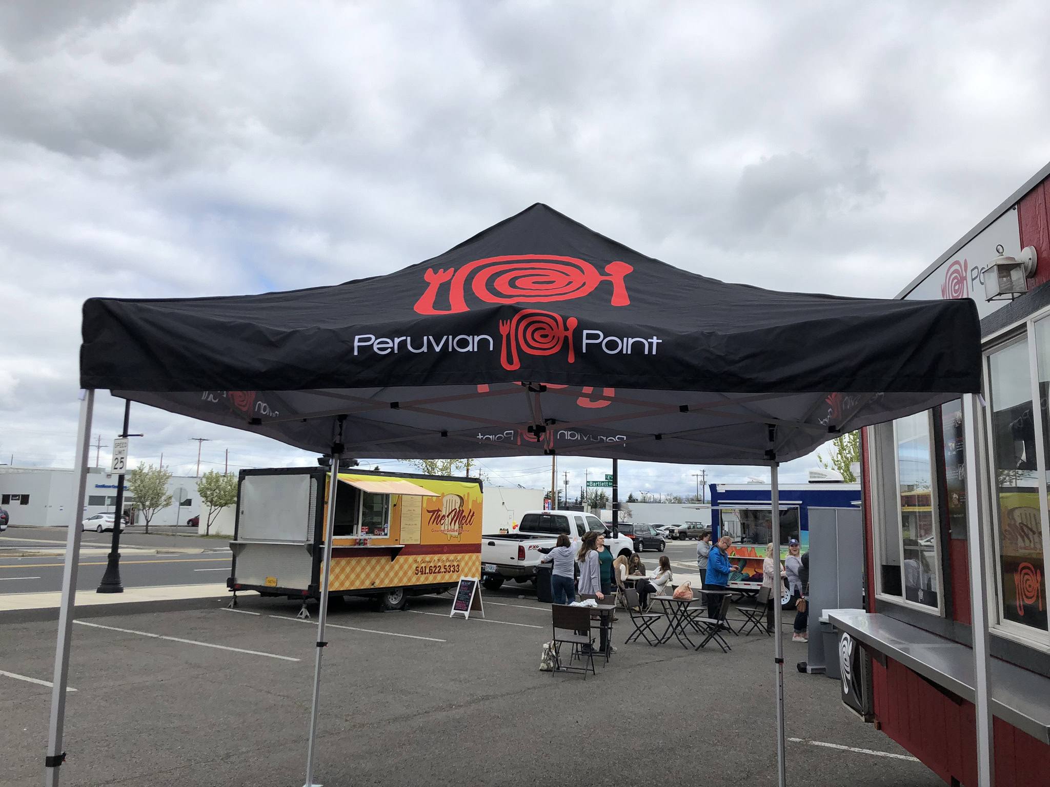 Outdoor event tent for Pronto Print Medford with seating and food trucks.