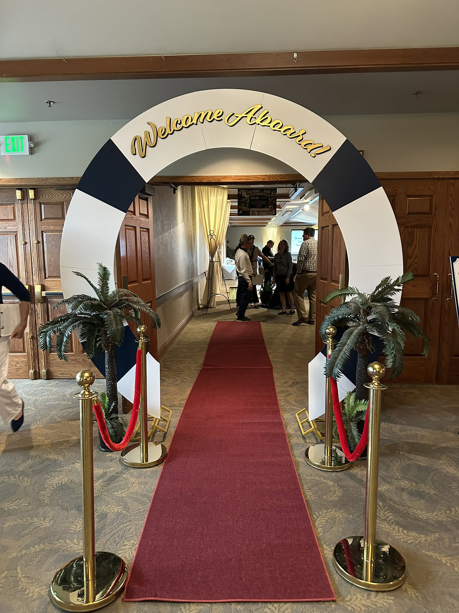Welcome arch at Pronto Print Medford with red carpet and tropical plants.